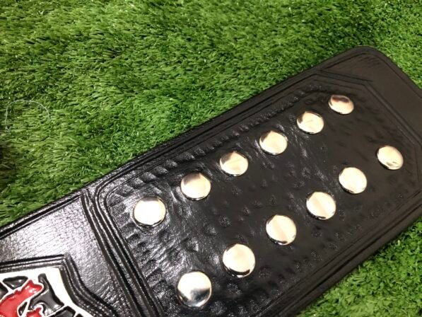 Close-up of black leather strap with dual snap closures and tooling pattern detail