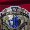 Close-up detail of WWE Intercontinental Championship Belt showing 4mm zinc buckle engraving, gold plating texture, leather stitching, and USA quality