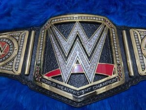 Close-up of WWE World Heavyweight Championship replica belt center plate with gold plating, clear stones and red accents